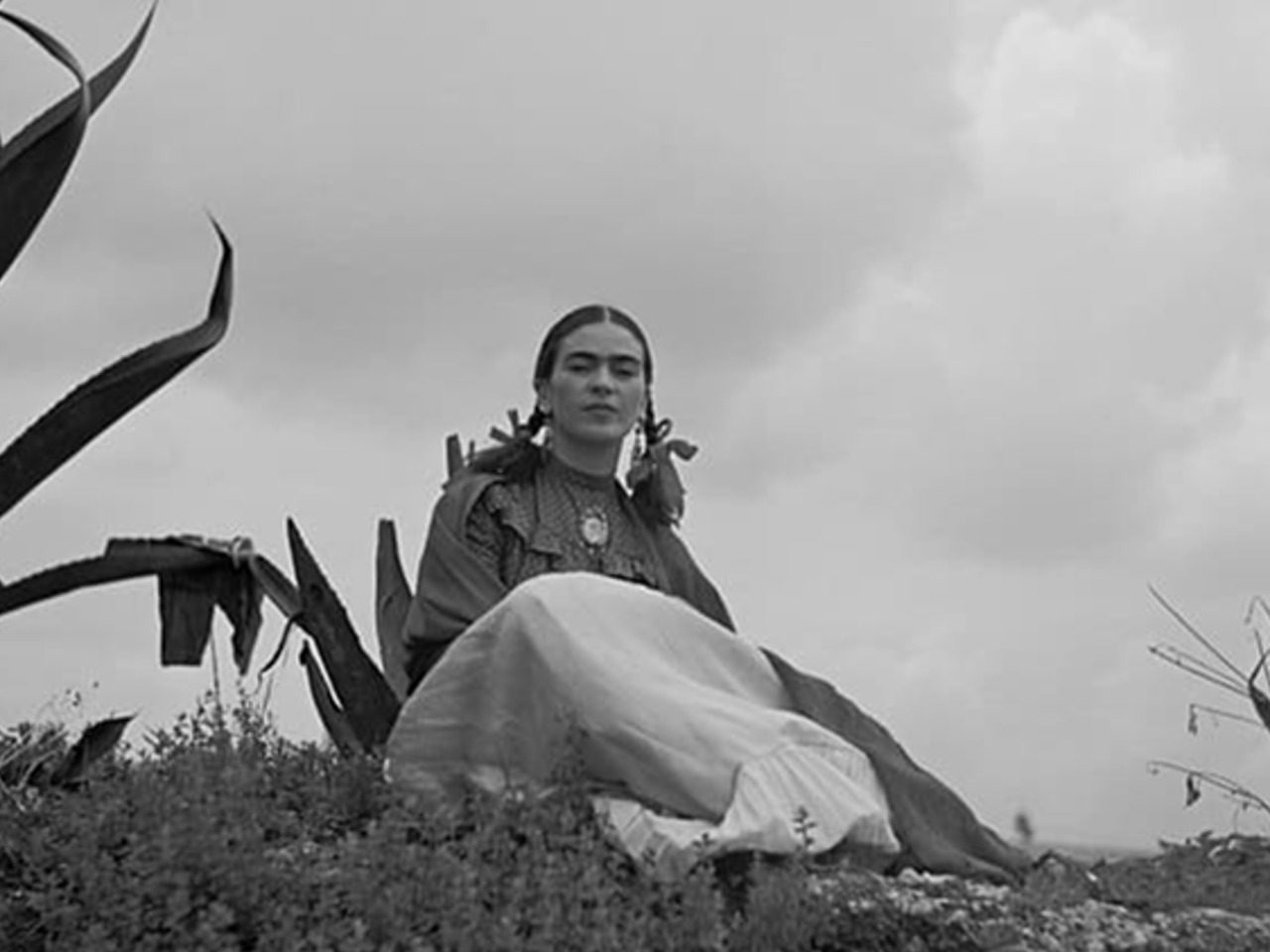 Photo en noir et blanc de Frida Kahlo assise près d'un agave