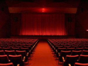 Photographie d'un théâtre avec un rideau et des sièges rouges