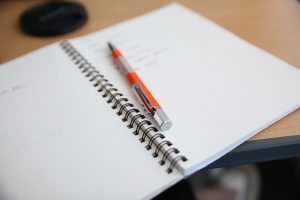 photographie d'un cahier ouvert et d'un stylo