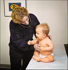 Photographie d'une pédiatre auscultant un bébé