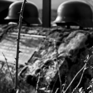 Image de guerre avec des casques de soldats posés sur ce qui pourrait être une tombe