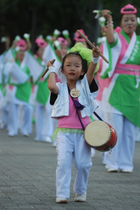 Photographie d'une fillette tapant sur un tambour dans un défilé