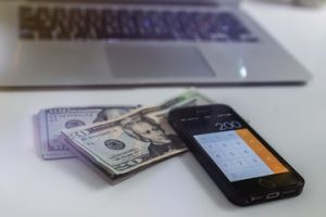 photographie d'un laptop, smartphone et billets
