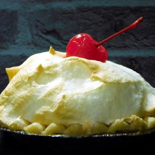 Photographie d'une tarte au citron surmontée d'une cerise