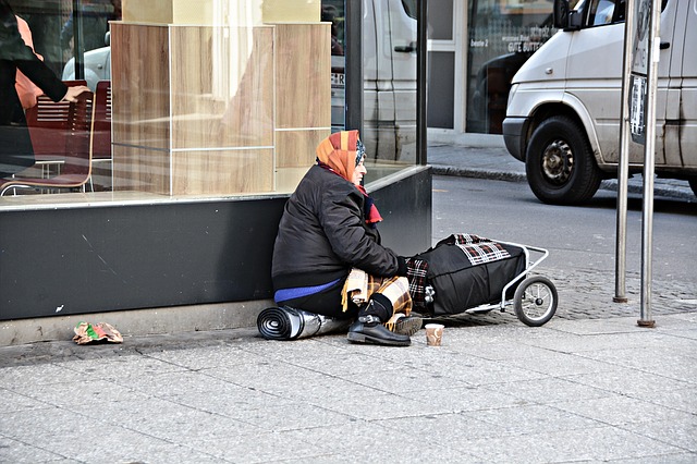 Photographie d'une femme assise au coin d'une rue avec ses paquets