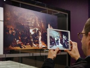 photographie d'un homme photographiant une oeuvre avec sa tablette