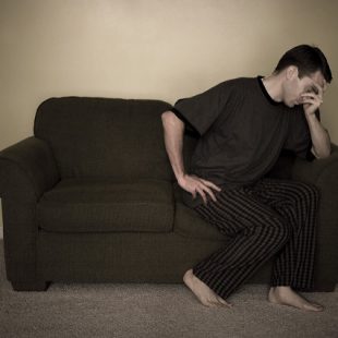 Photographie d'un homme prostré sur un canapé