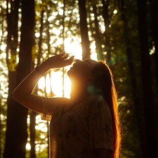 Femme en contre-jour dans une forêt.