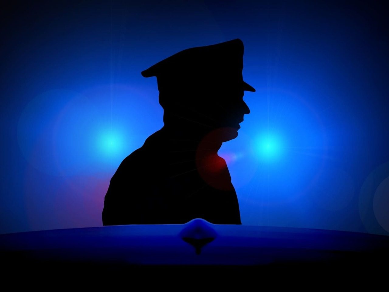 Silhouette d'un policier éclairée par une lumière bleue.