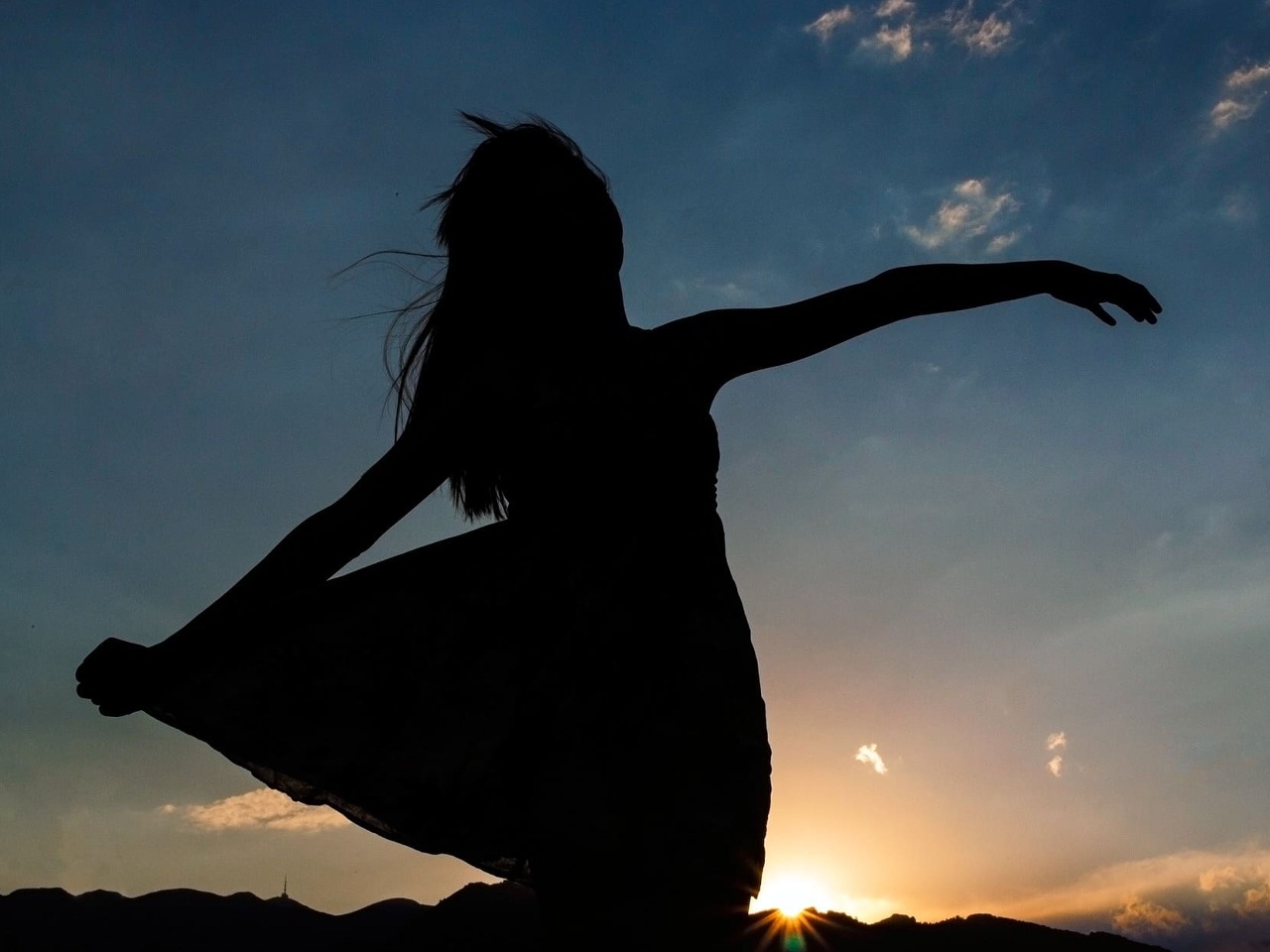 Silhouette de femme au soleil couchant.