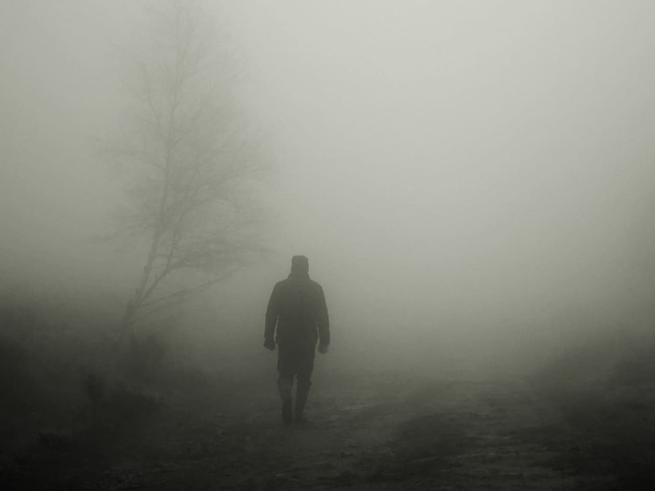 Silhouette d'une personne marchant dans le brouillard.