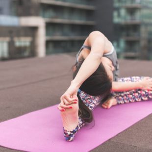 personne qui s'étire sur un tapis de yoga
