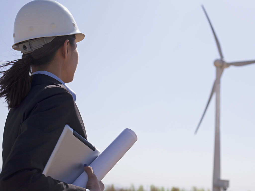 feme ingénieur de profil devant une éolienne