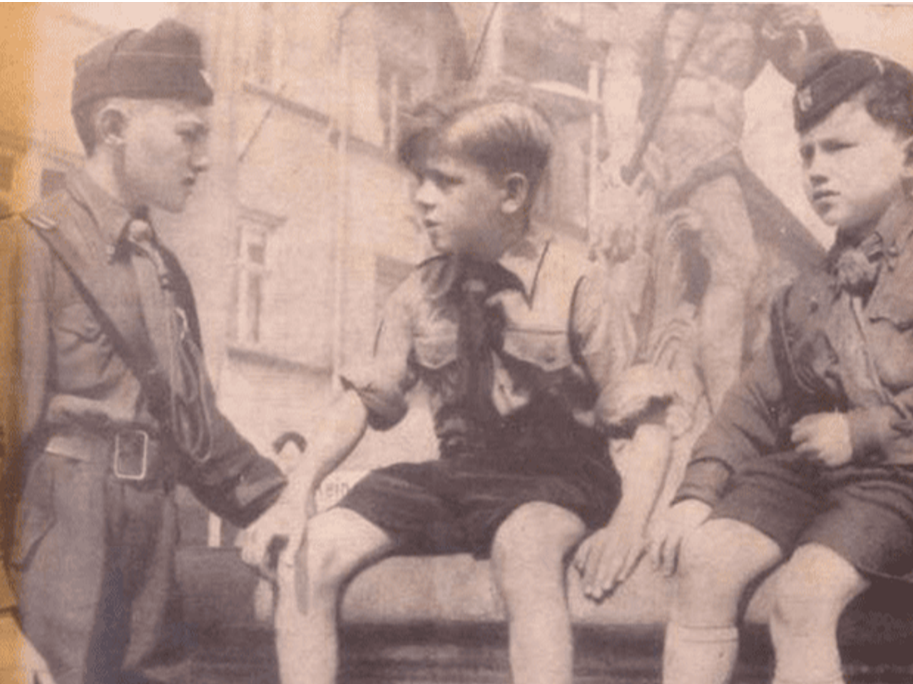 Photo noir et blanc de deux enfants membres des Ustaše Youth entourant un garçon des Jeunesses hitlériennes