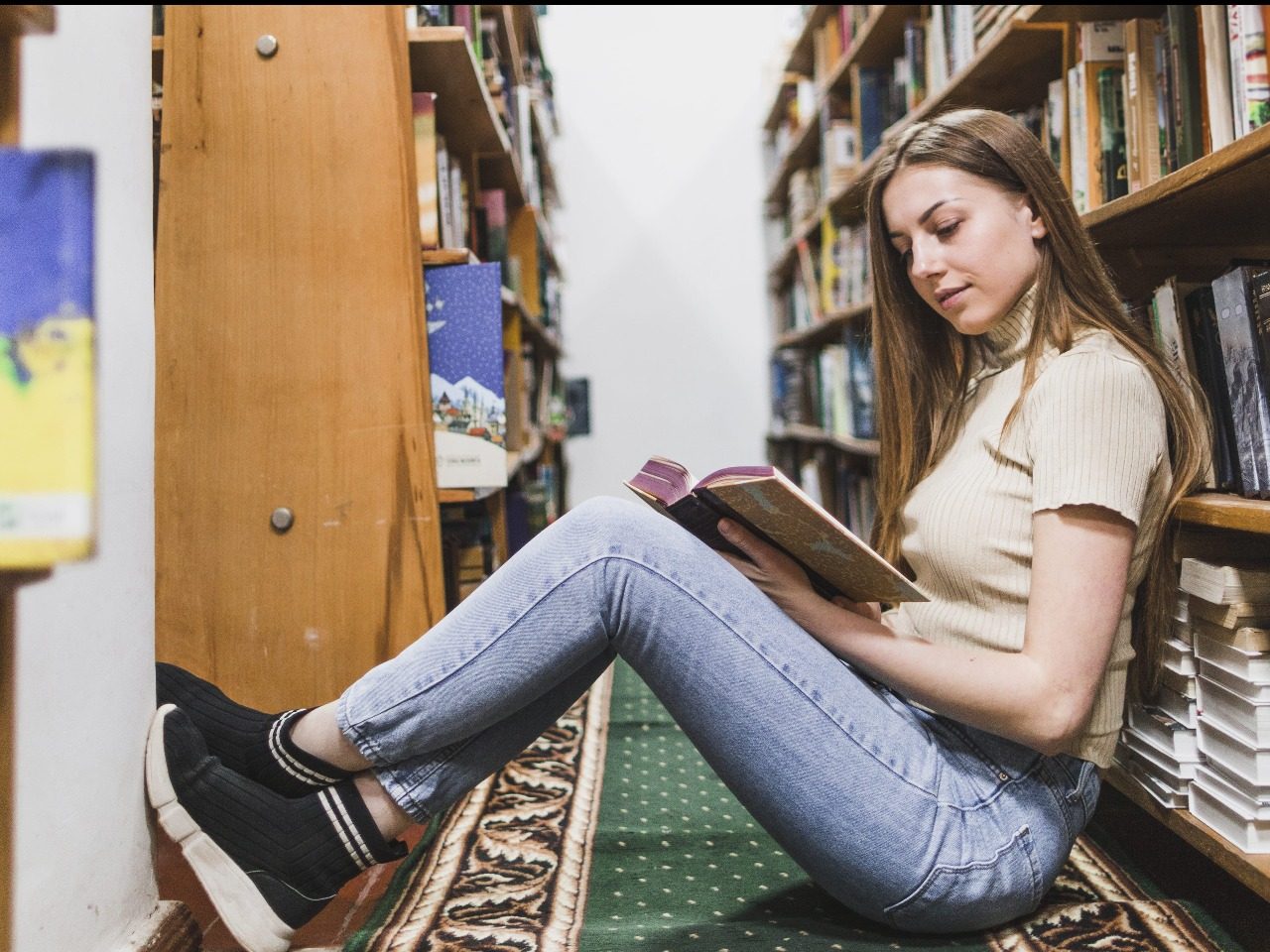 adolescente en train de lire assise par terre