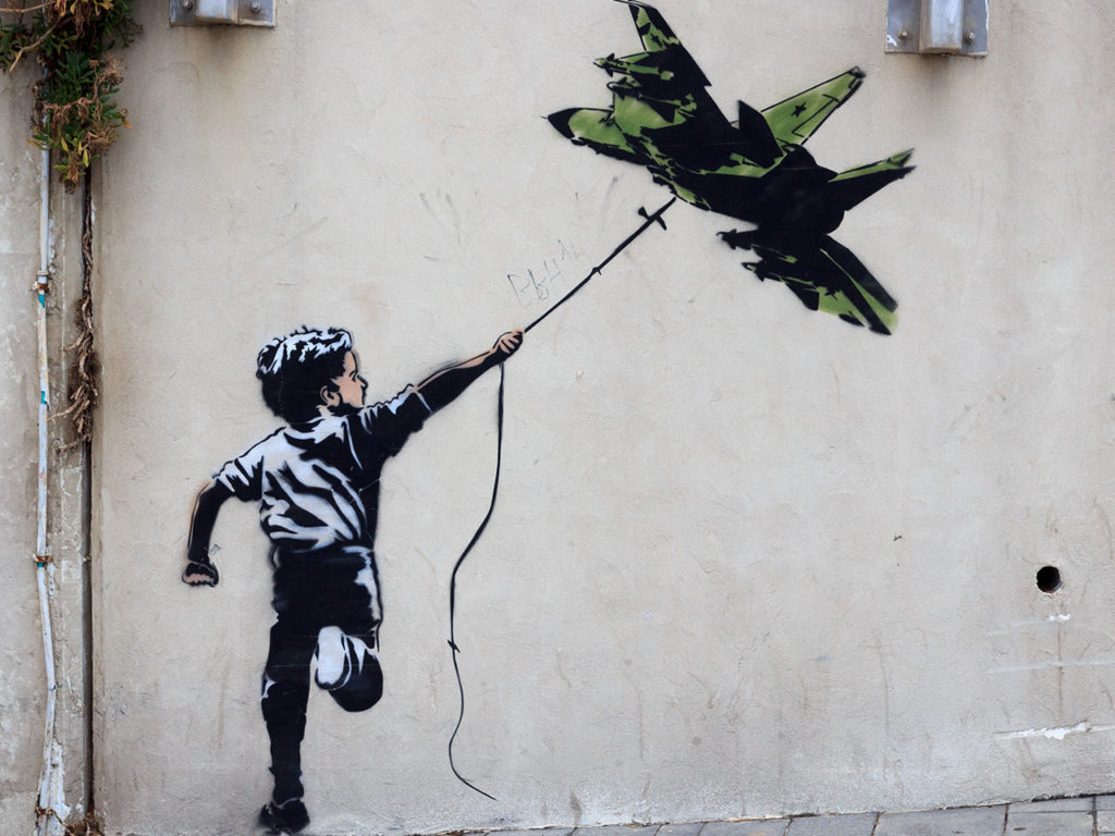 Graffiti d'un enfant avec un avion de chasse en guise de cerf-volant à Tel Aviv