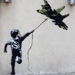 Graffiti d'un enfant avec un avion de chasse en guise de cerf-volant à Tel Aviv