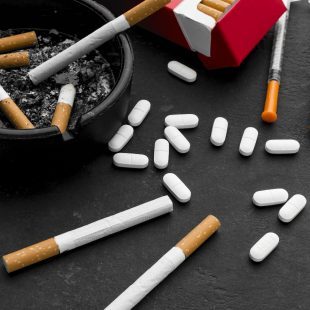 Présentation de produits addictifs posés sur une table , cigarettes, médicaments, seringues