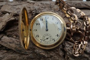 Montre gousset ouvert dont les aiguilles indiquent 12H