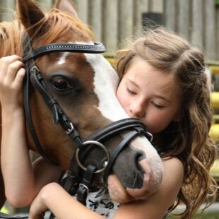 Petite fille caressant un cheval.