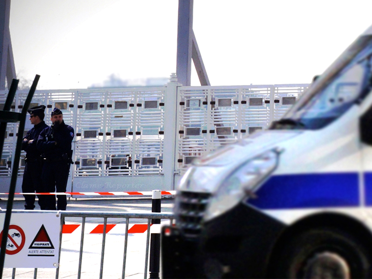 photo d'un car de police devant une barrière et un bâtiment