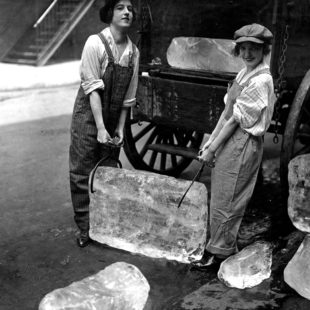 Photographie de deux femmes portant un bloc de glace