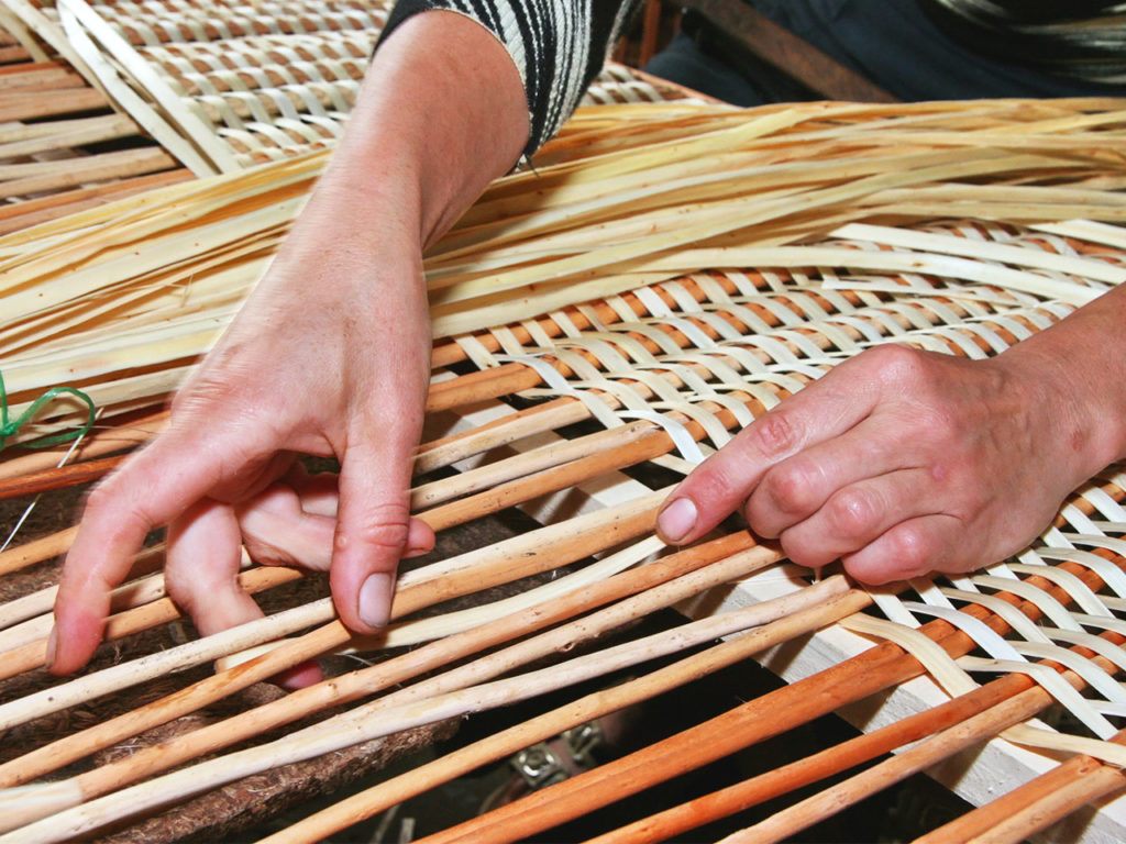 gros plan sur des mains confectionnant manuellement un panier
