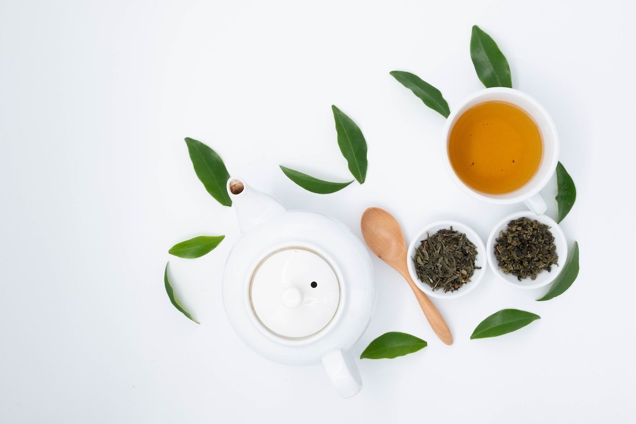 tasse de thé avec quelques feuille de thé verts autour