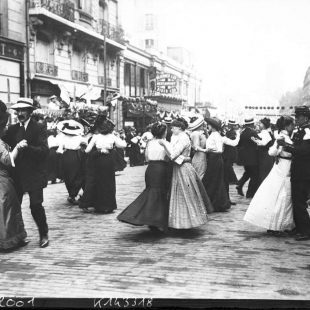 Photographie en noir et blanc lors du Bal du 14 juillet 1912 par l' Agence Rol Hommes et femmes en train de danser dans une rue