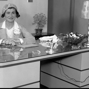 Coco Chanel assise à un bureau lors d'une visite à Los Angeles, le 18 mars 1931