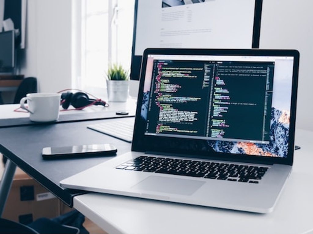 Photo d'un écran d'ordinateur sur un bureau faisant apparaitre des lignes de code