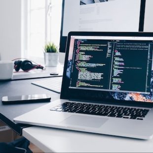 Photo d'un écran d'ordinateur sur un bureau faisant apparaitre des lignes de code