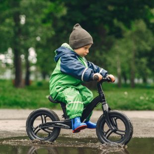 petit garçon sur son vélo au milieu d'une flaque d'eau, image de prostooleha sur Freepik