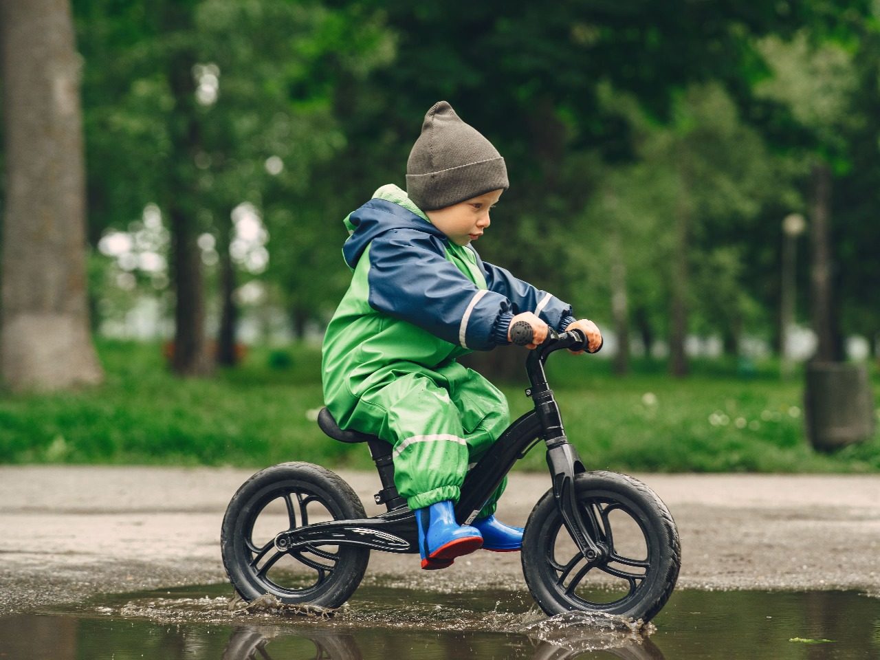 petit garçon sur son vélo au milieu d'une flaque d'eau, image de prostooleha sur Freepik