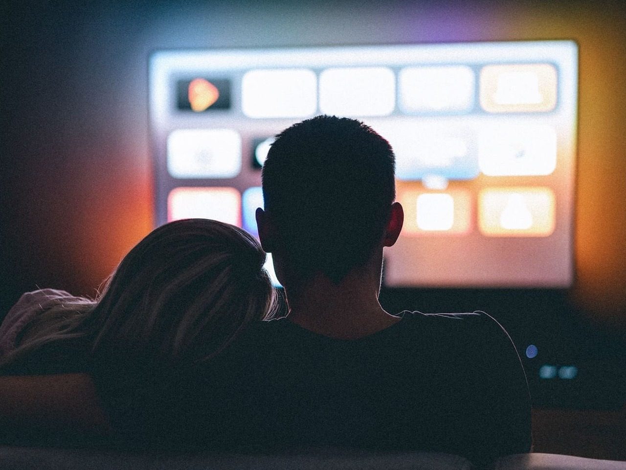 Photo de couple sur un canapé devant un écran