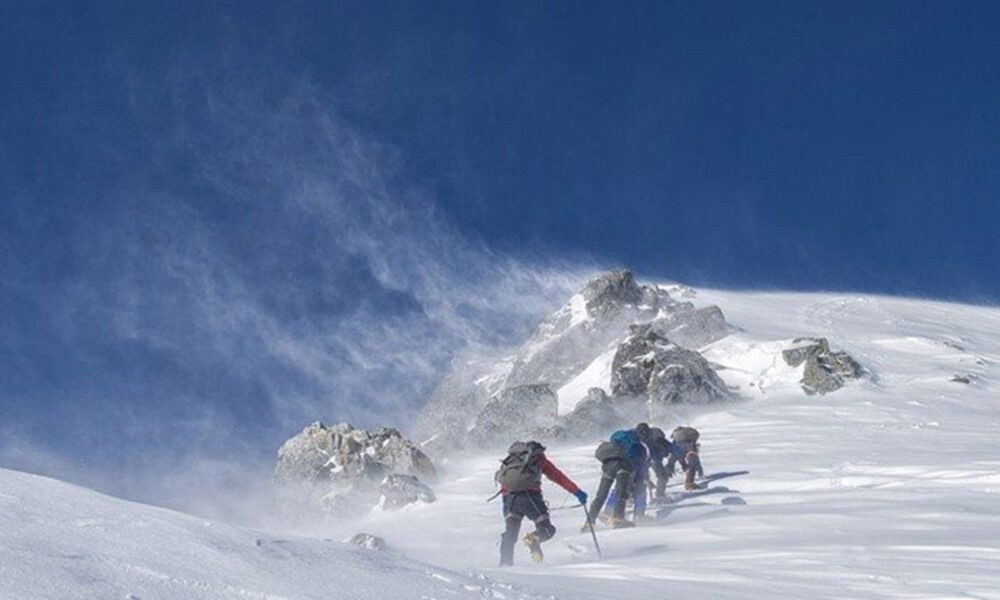 Alpinistes près d'un sommet enneigé sur fond de ciel bleu