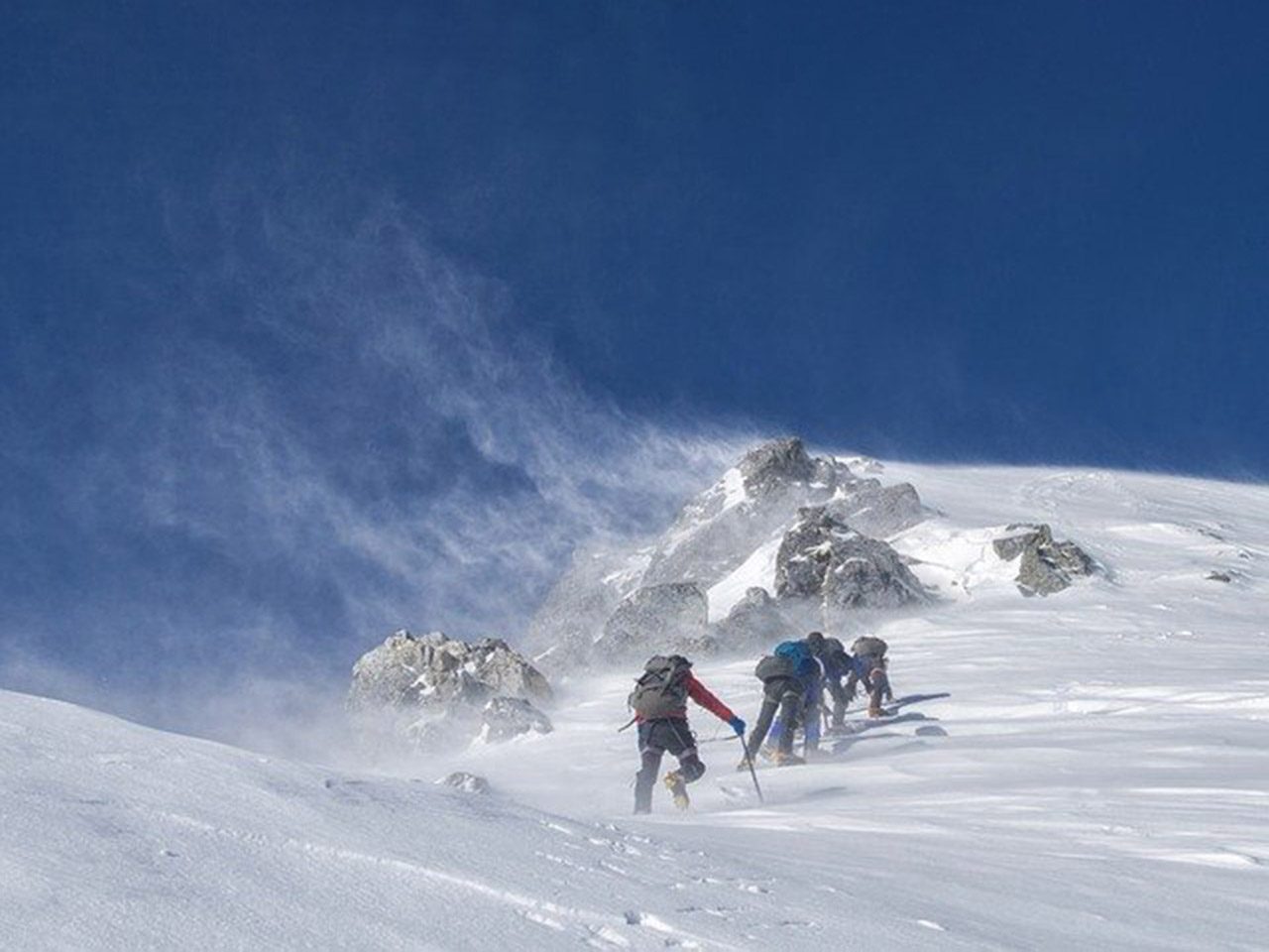 Alpinistes près d'un sommet enneigé sur fond de ciel bleu