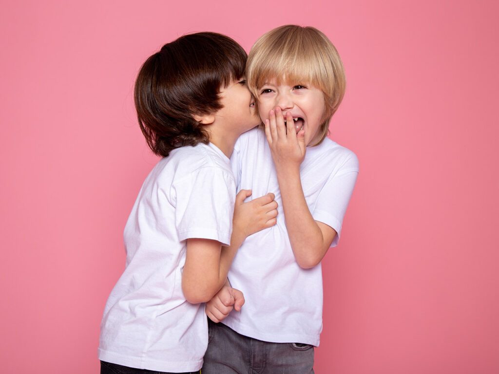 2 enfants riant sur fond rose