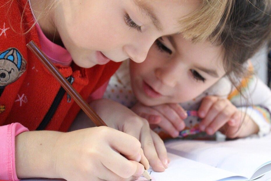 Deux enfants penchés en train de dessiner sur un cahier