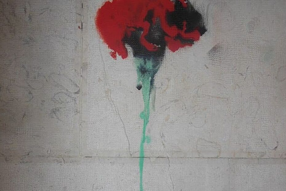 Dessin d'œillet au pochoir sur un mur commémorant le 25 avril 1974, révolution portugaise. Inscription "Fascismo Nunca Mais".
