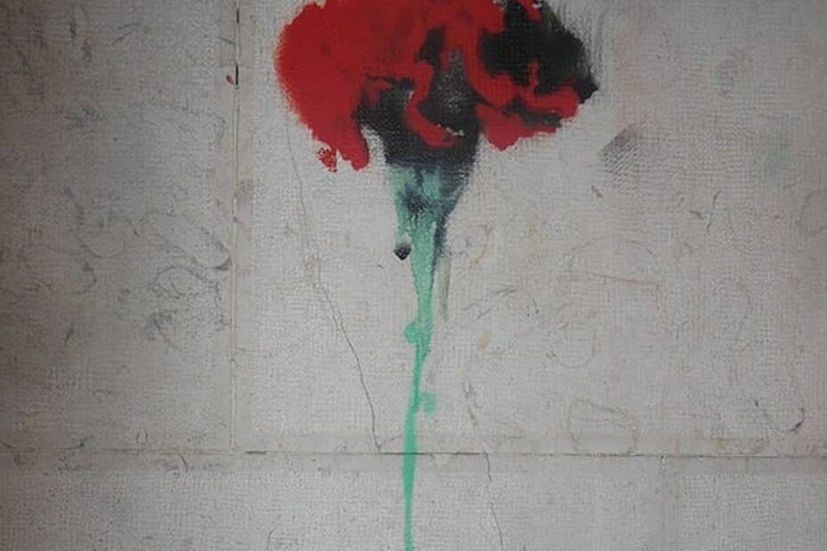 Dessin d'œillet au pochoir sur un mur commémorant le 25 avril 1974, révolution portugaise. Inscription "Fascismo Nunca Mais".