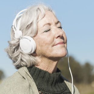 Photo de dame âgée souriante, un casque sur les oreilles