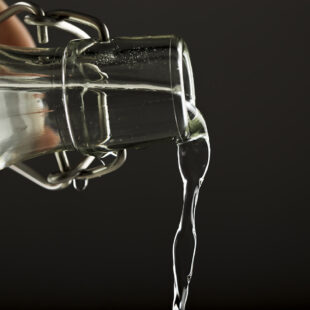 Main tenant une bouteille en verre et versant de l'eau