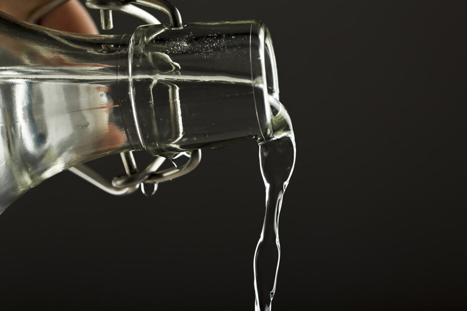 Main tenant une bouteille en verre et versant de l'eau