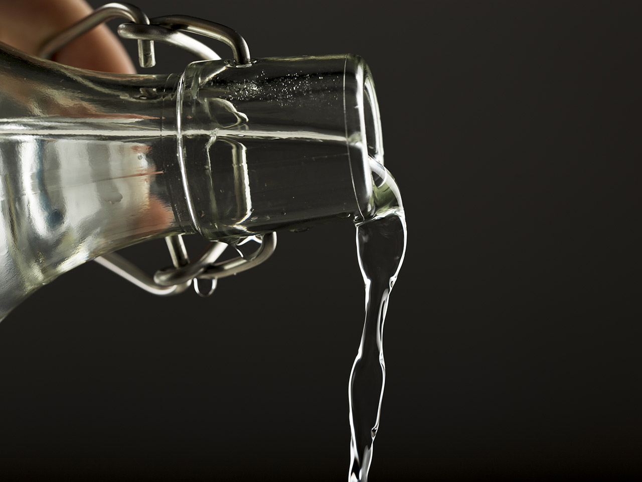 Main tenant une bouteille en verre et versant de l'eau