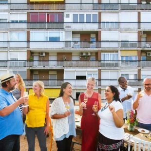 Un groupe de personnes prend l'apéritif sur une terrasse donnant sur un immeuble.