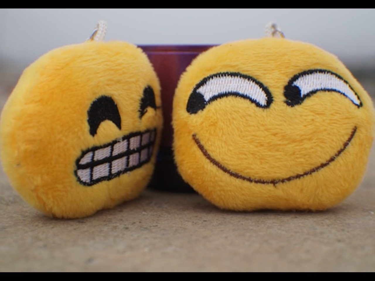 Photo de 2 smiley en peluche qui présentent chacune un rire différent