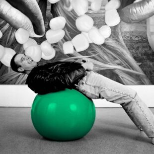 Photographie noir et blanc de Jeff Koons adossé à sur un ballon. Seul le ballon est colorisé en vert (couleur verte reprise des tulipes de JK.)