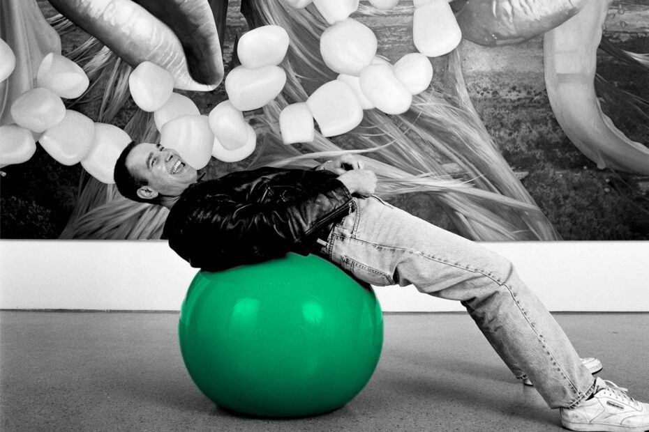 Photographie noir et blanc de Jeff Koons adossé à sur un ballon. Seul le ballon est colorisé en vert (couleur verte reprise des tulipes de JK.)