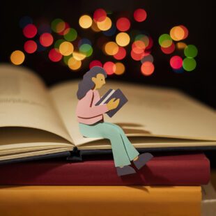 Image représentant une personne en papier assise en train de lire sur une pile de livres. En haut de sa tête se trouve des confettis lumineux de couleurs.